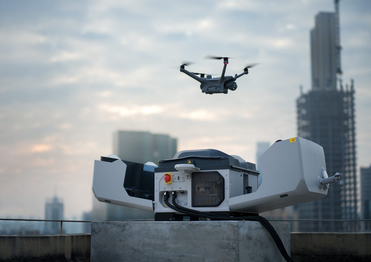 Dron startující z pevného doku na střeše budovy nad městskou zástavbou