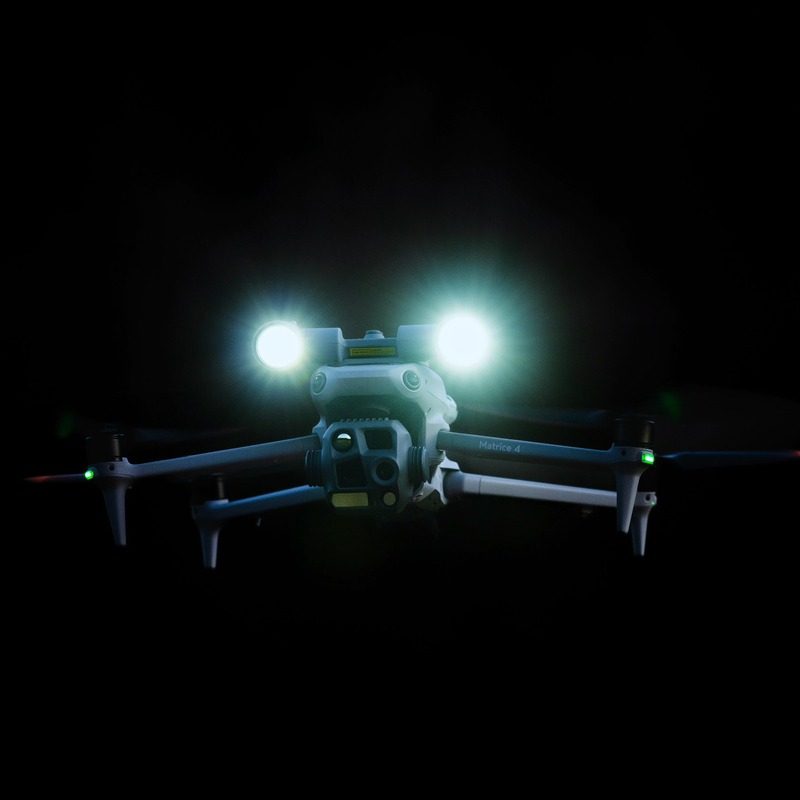 Dron s rozsvícenými reflektory v noci